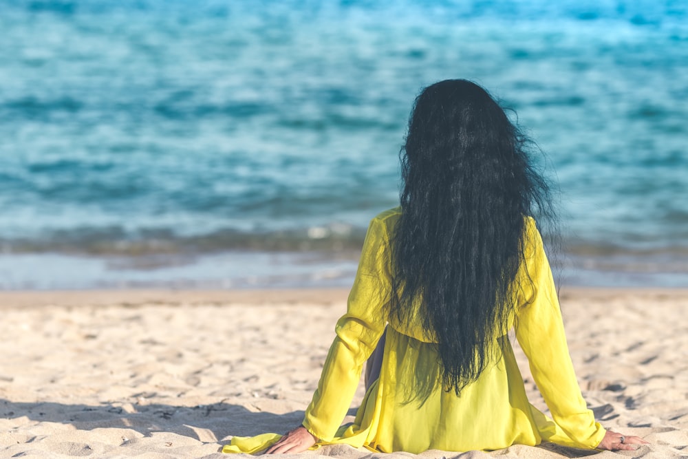 Mujer sentada en la arena cerca de la orilla del mar