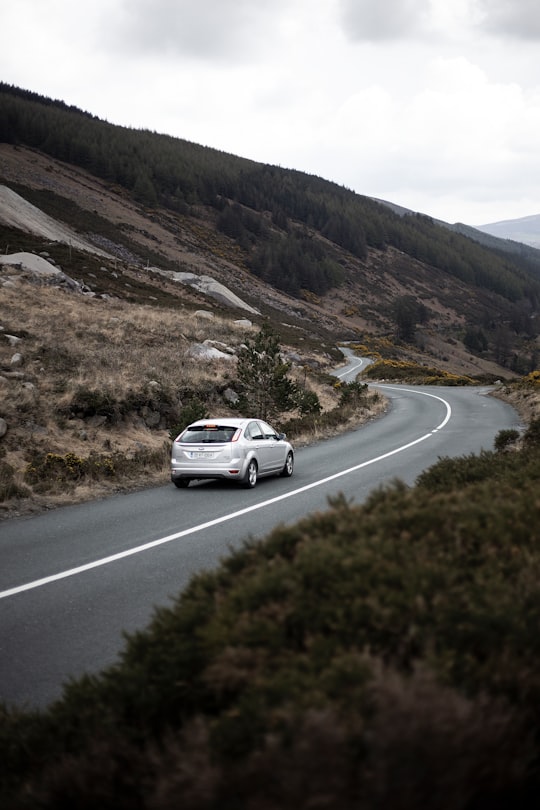 photography of moving silver sedan on road in Wicklow Mountains National Park Ireland