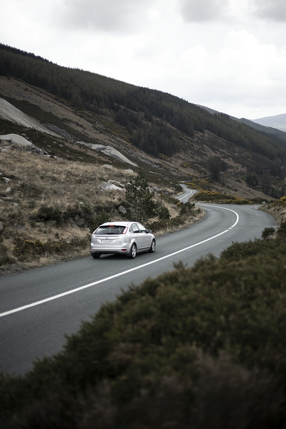 photography of moving silver sedan on road