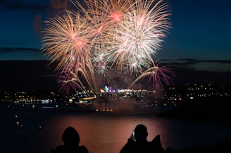 silhouette of two person taking photo of fireworks