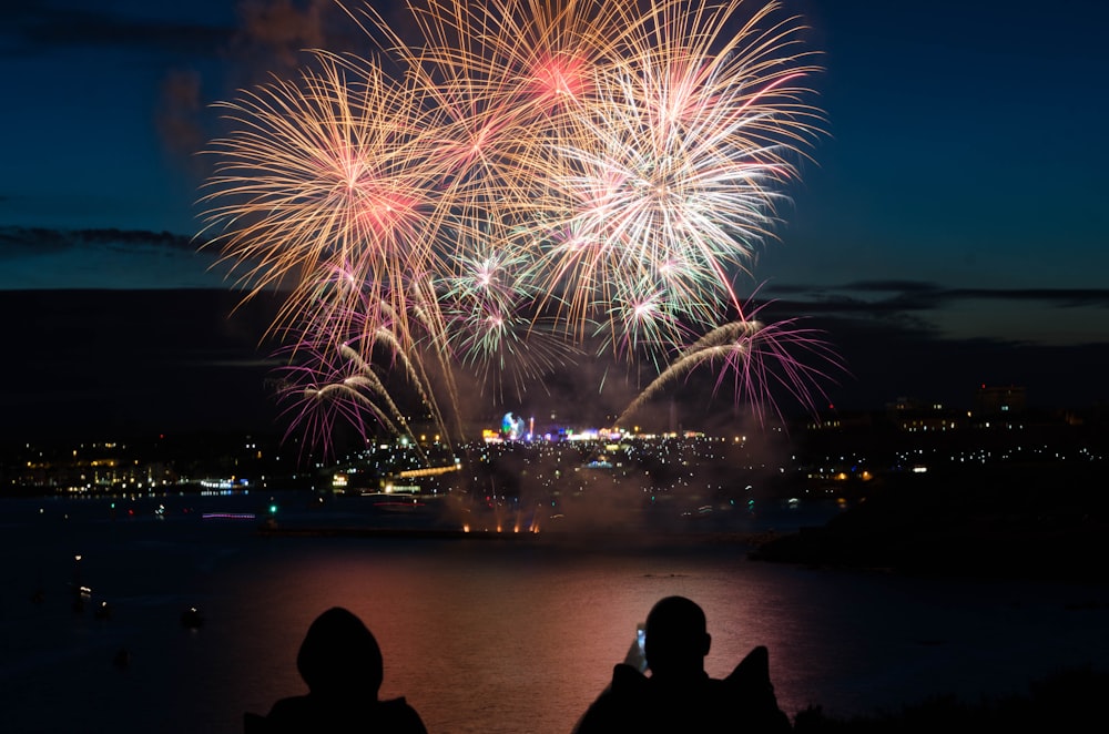 silhouette di due persone che scattano foto di fuochi d'artificio