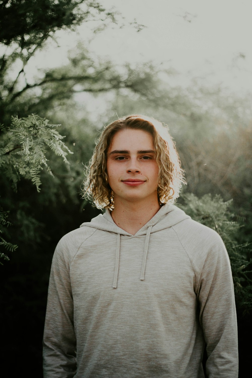 man in gray hoodie near trees at daytime