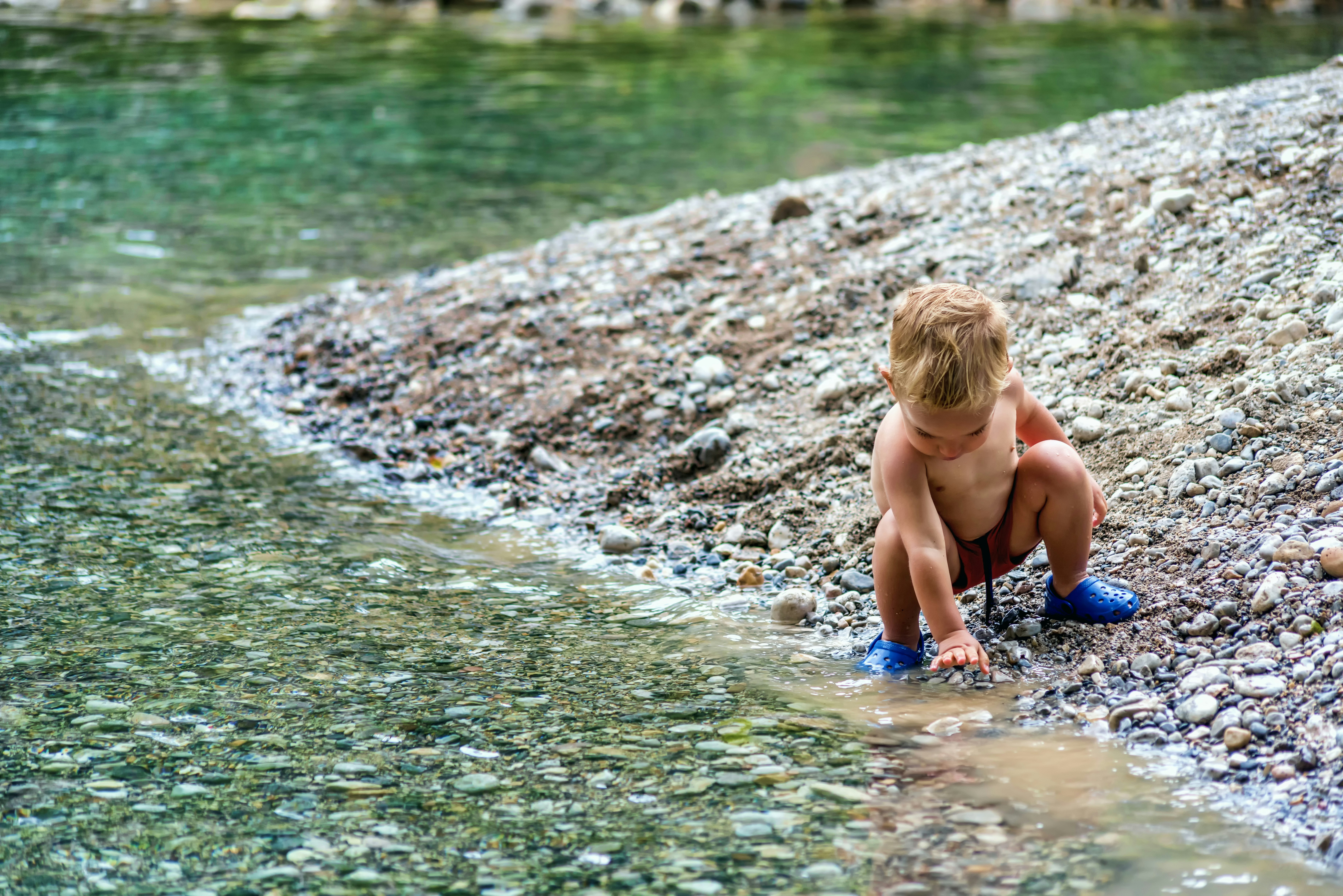 baby playing beside body of water
