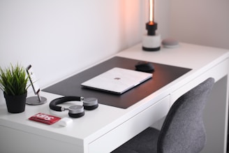 A cozy, minimal workspace with a softly glowing lamp and headphones resting on a clean desk.