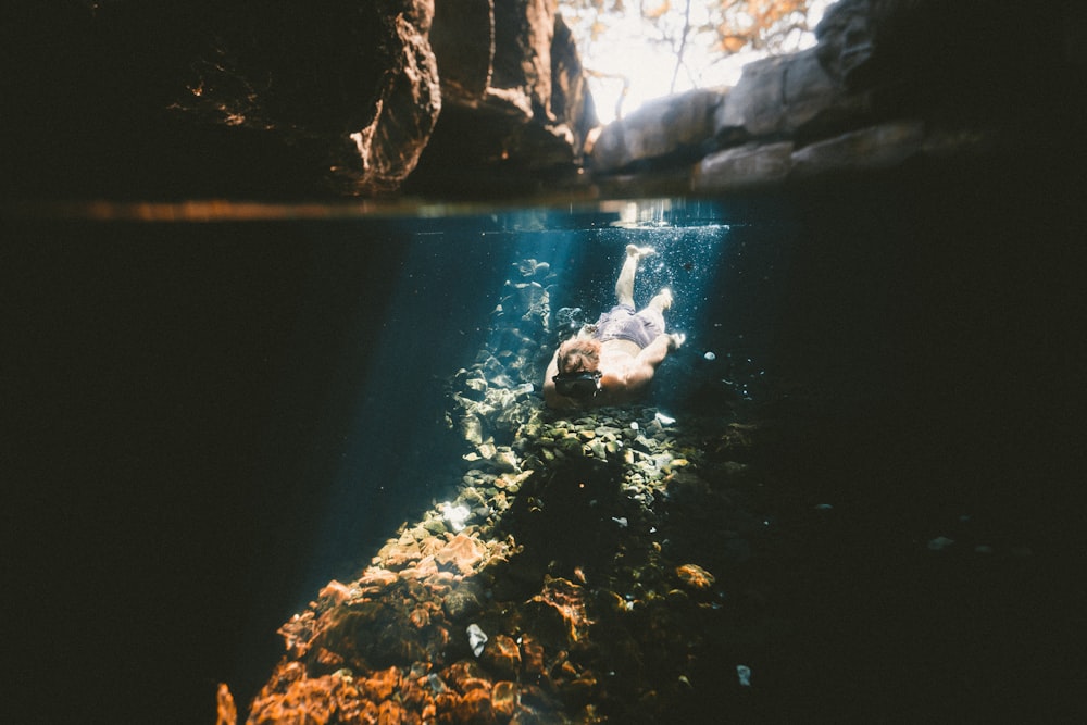 man diving on the river with rock formation