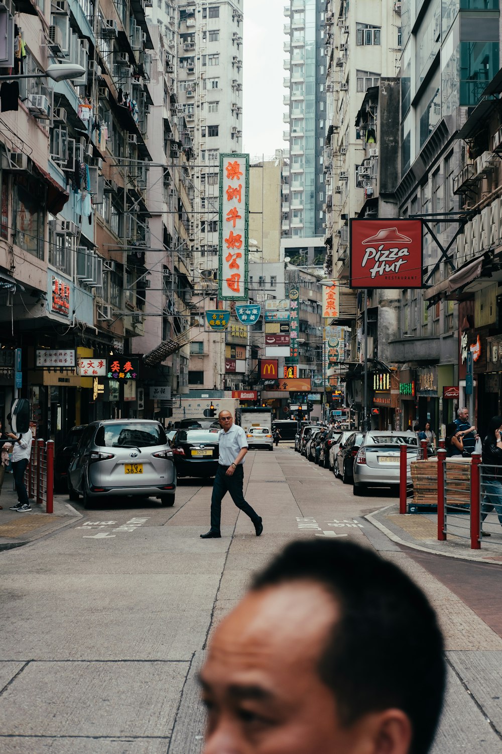 a man walking down a street next to tall buildings