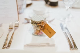 clear glass mason jar on top of white table napkin between forks and knives