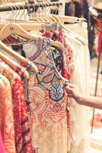 a woman is trying to find a dress on a rack