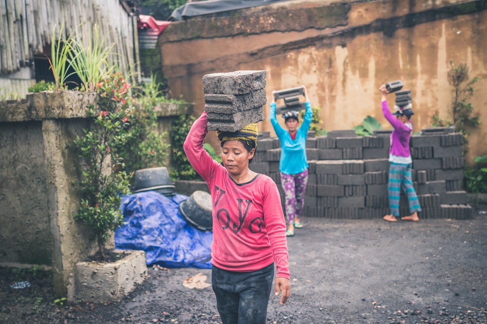 women carrying a stone bricks