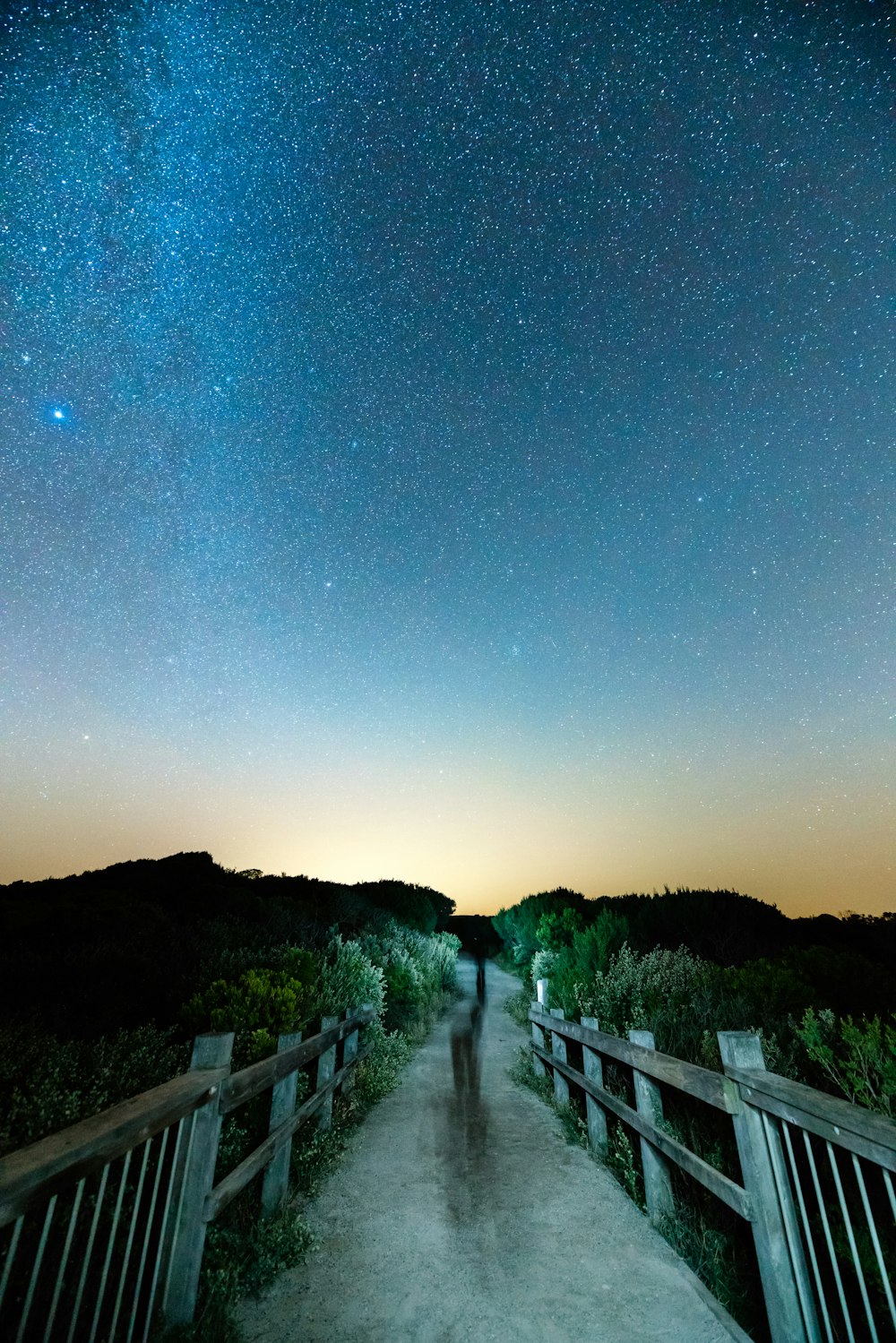 夜空の下の灰色の木製の橋