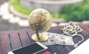 gray desk glove above U.S dollar beside iPhone and white airpods