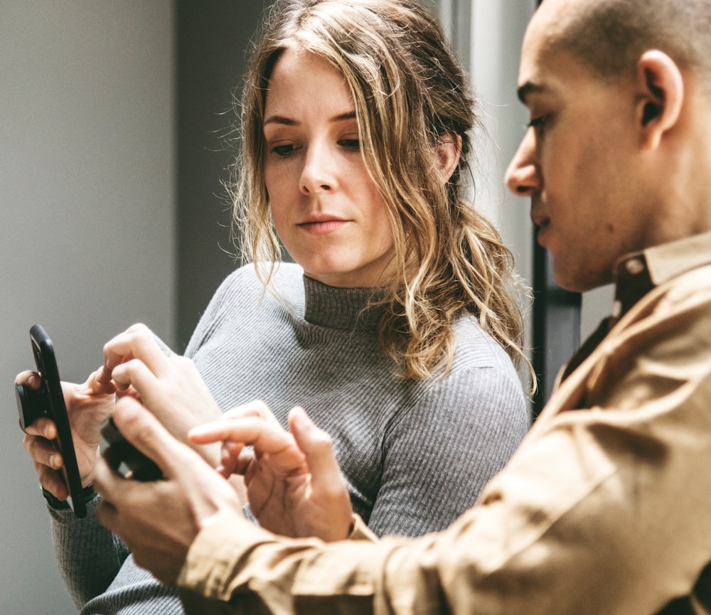 man and woman holding smartphones