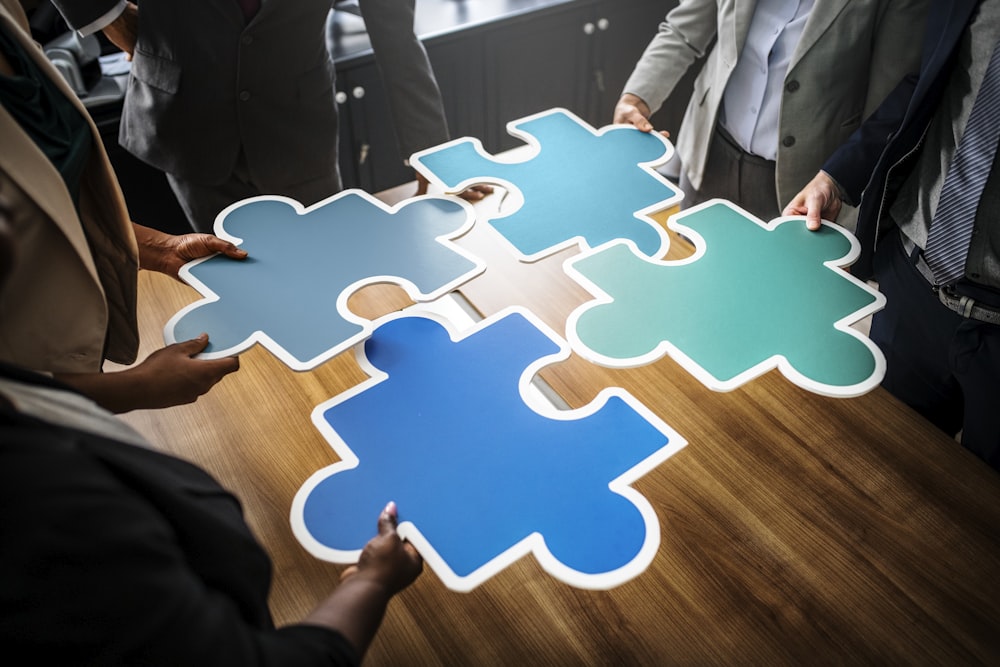 four person holding assorted-color jigsaw puzzles inside room