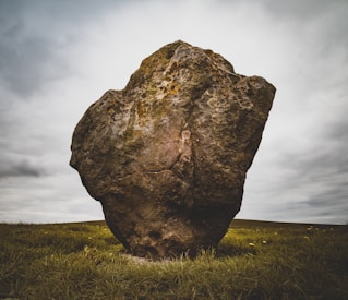 brown rock formation surrounded by green grass