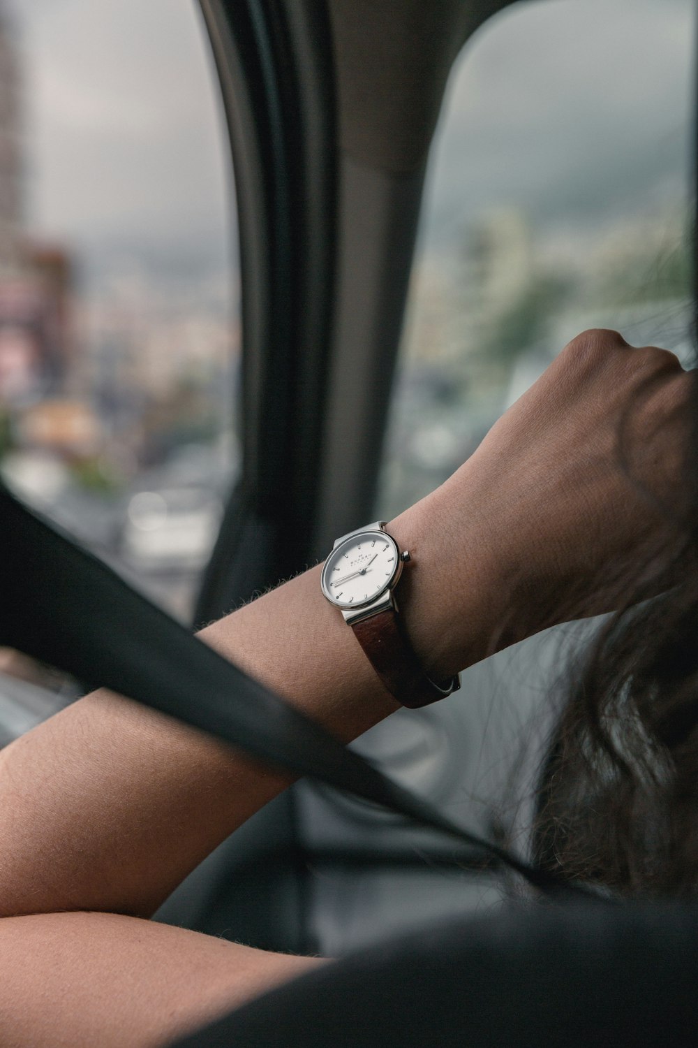 person wearing round silver-colored analog watch with leather band