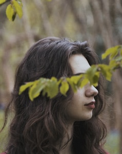 woman's eyes covered by green leaves