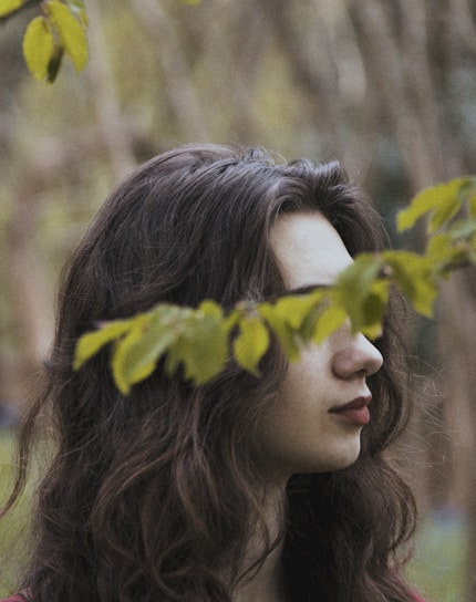 woman's eyes covered by green leaves