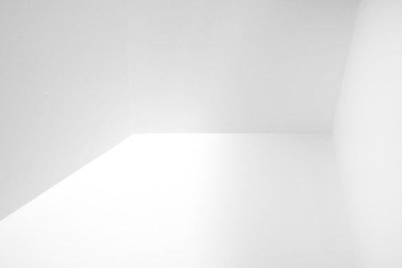 A minimalist image featuring clean geometric lines and smooth surfaces, where two walls and a ceiling intersect, creating a sharp corner. The surfaces appear smooth and solid, and the lighting is evenly distributed, enhancing the sense of simplicity and clarity.