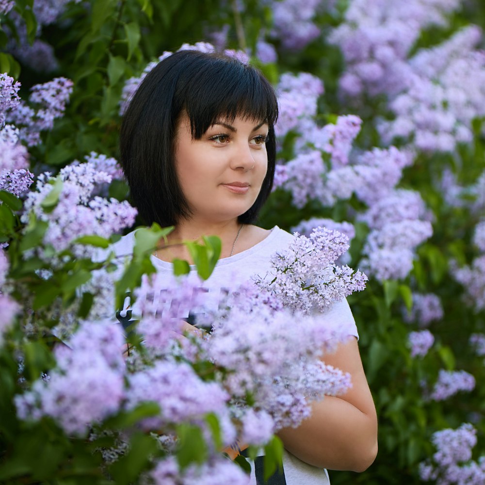 woman in white top standing beside lavender flowers