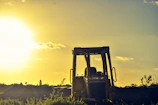 Heavy machinery smoothing a road surface at sunset, casting blue and gold hues.