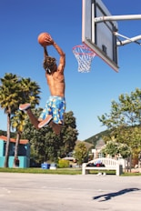 person dunking ball under blue sky during daytime