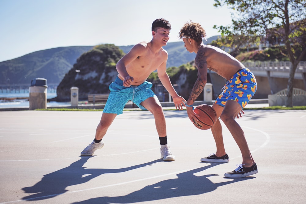 two topless men playing basketball during daytime