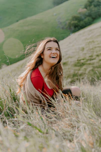 depth photography of woman in red top sitting on green grass