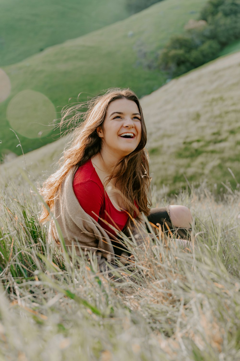 depth photography of woman in red top sitting on green grass