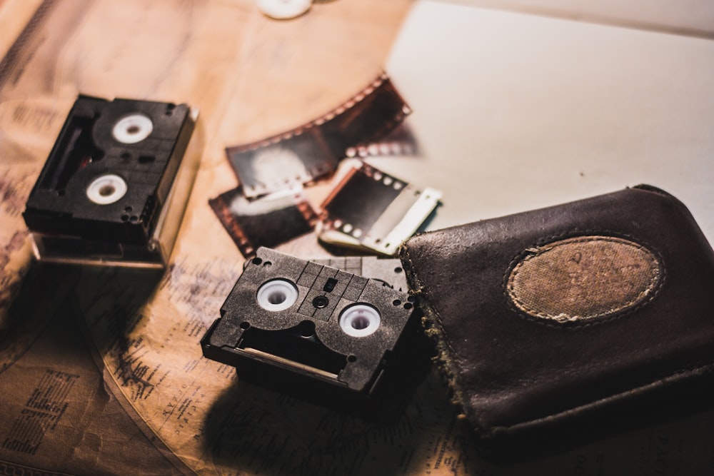 black leather bi-fold wallet beside cassettes