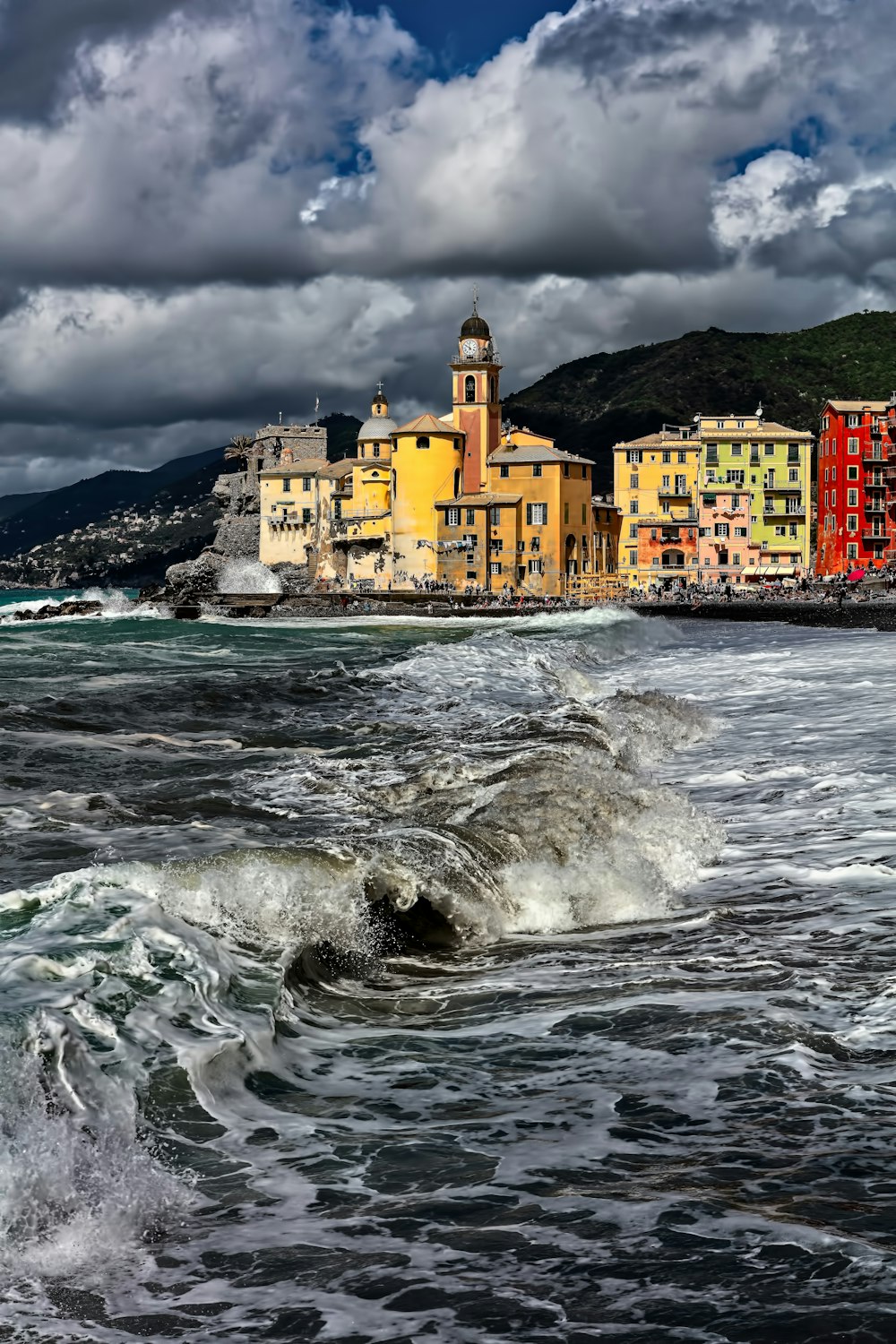 yellow concrete buildings near mountain viewing sea under white cloudy skies