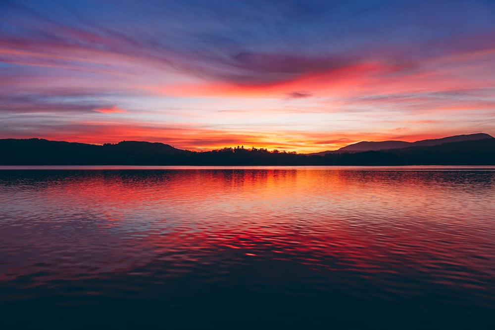 silhouette photo of body of water and mountain