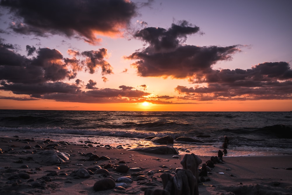 shore with stones near ocean at golden hour