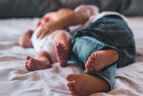 a close up of a childlaying on a bed with a baby