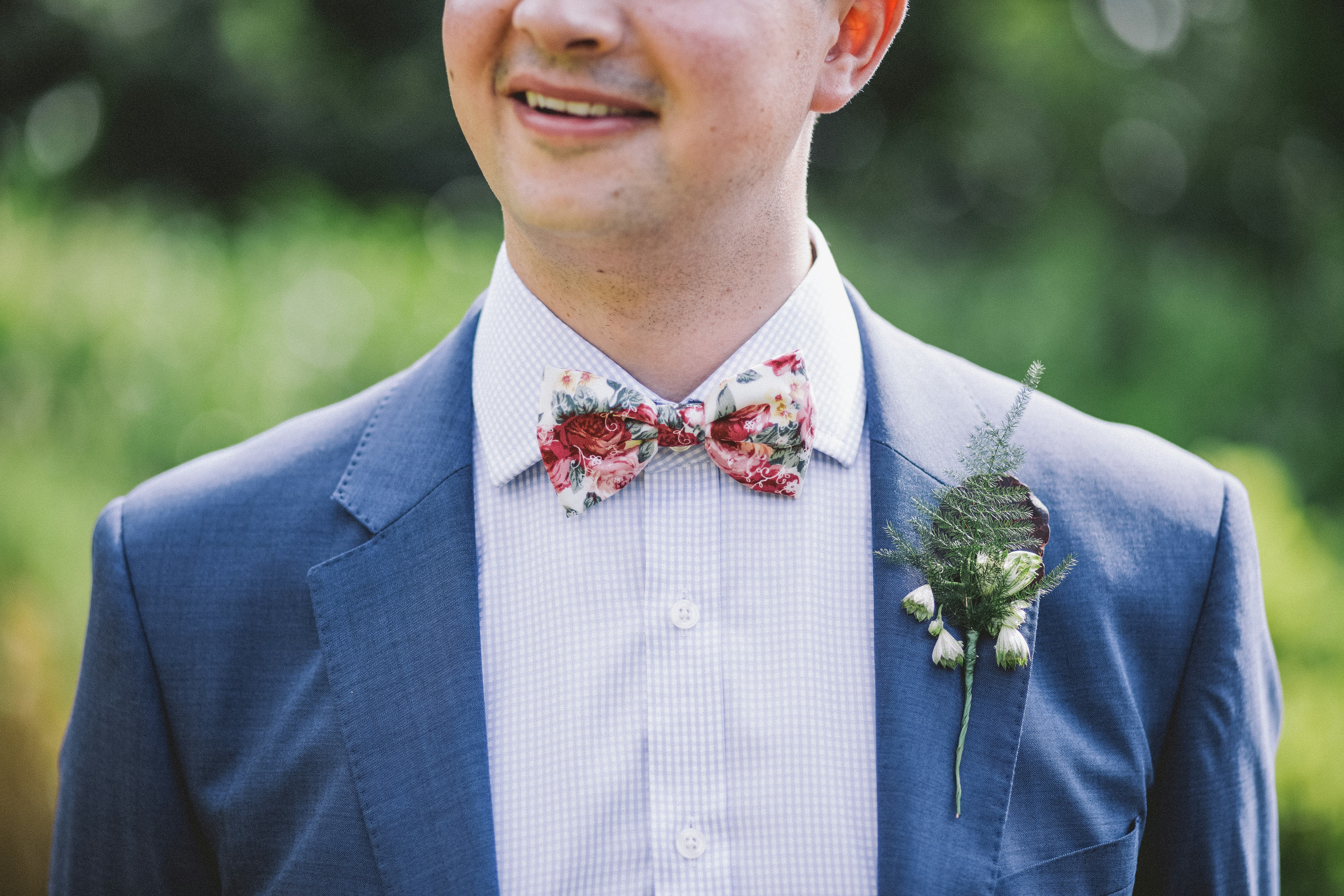 man wearing blue notched-lapel blazer with red and white bowtie at daytime