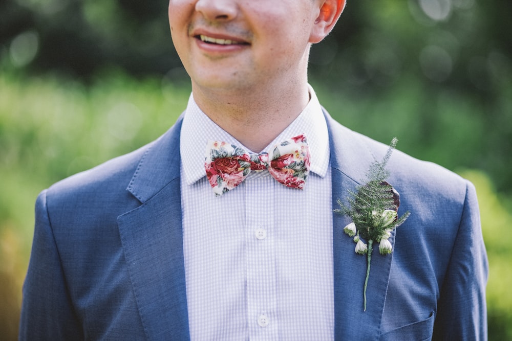 man wearing blue notched-lapel blazer with red and white bowtie at daytime