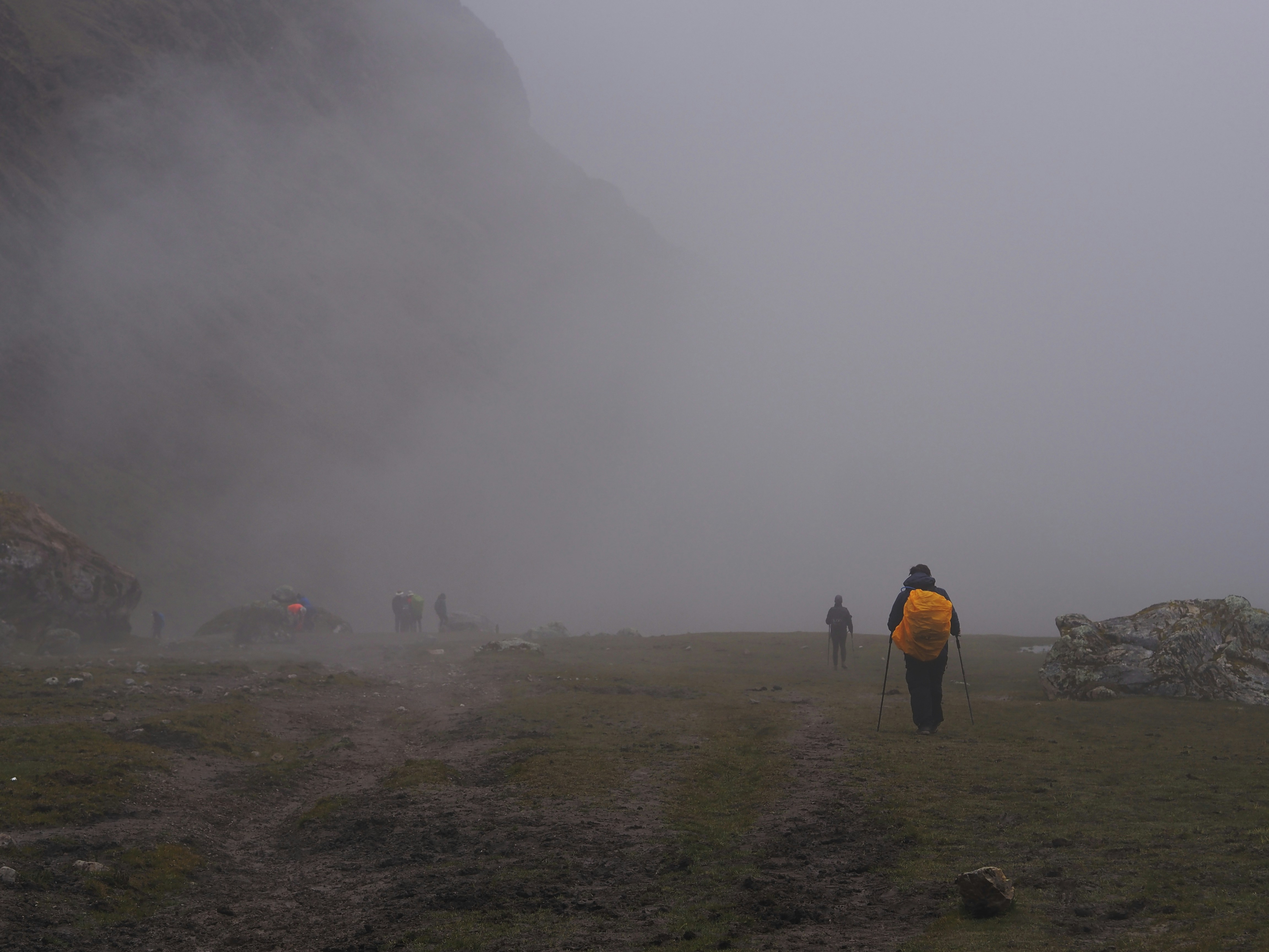 Trekker with backpack on Mount Kenya trail, misty alpine landscape, glacial rocks