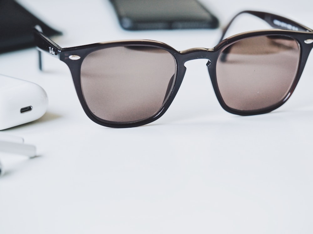 gafas de sol marrones sobre mesa de madera blanca