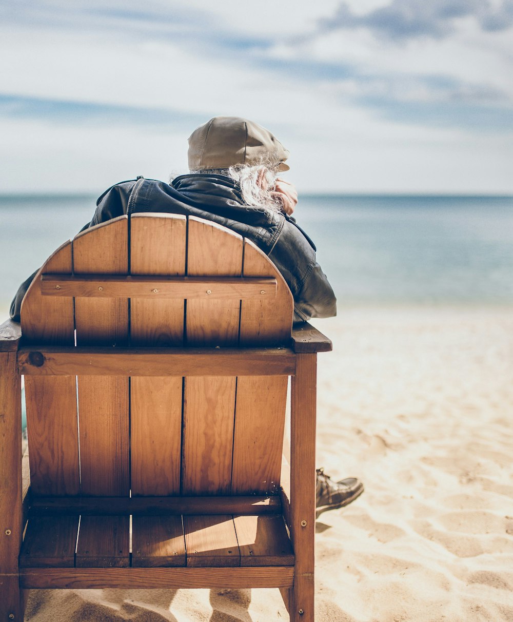 바닷가에서 갈색 나무 의자에 앉아있는 사람