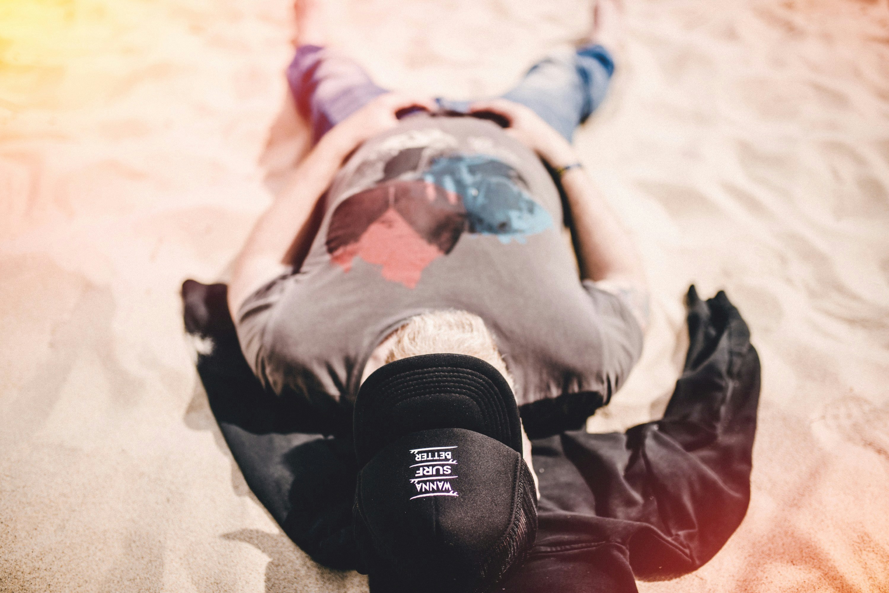 man in gray shirt lying on sand