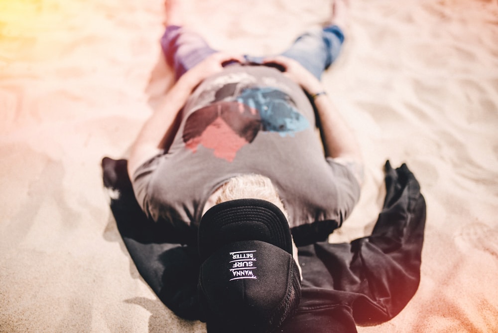 man in gray shirt lying on sand