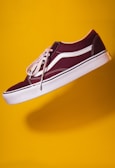 unpaired maroon plimsoll on top of yellow textile