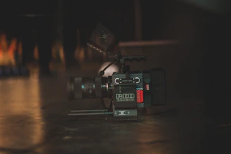 A professional camera resting on a wooden table surrounded by lenses and photography gear.