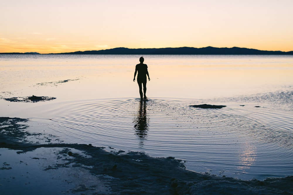 silhouette of person standing on body of water