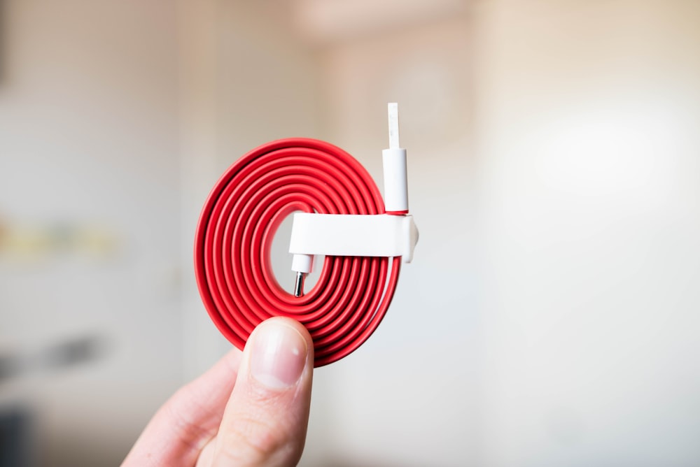 person holding white and red cable