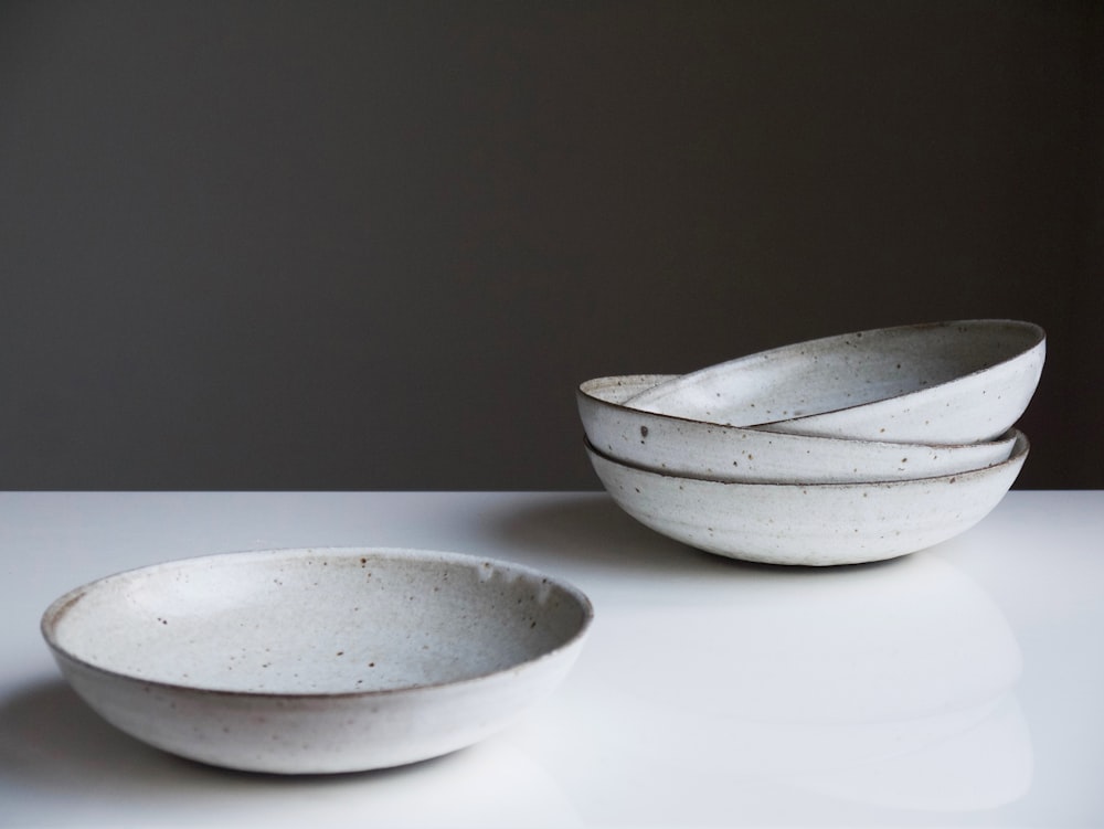 four round white ceramic bowls on white surface