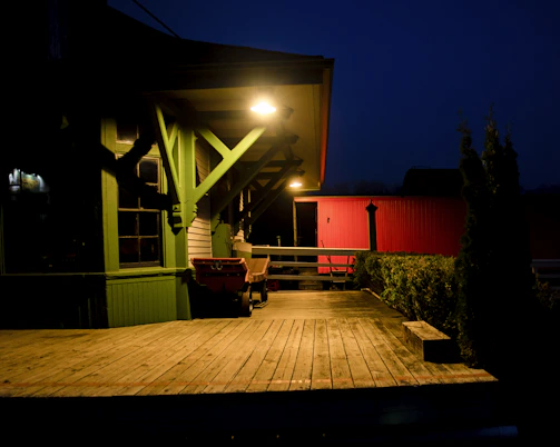 A newly built open porch with sloped roof and recessed lighting glowing warmly at dusk.