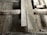A detailed view of a wooden floor structure with overlapping planks and visible beams. The boards and beams appear weathered and aged, possibly part of a construction or renovation project. The surface shows signs of wear and some dust accumulation.