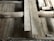 A detailed view of a wooden floor structure with overlapping planks and visible beams. The boards and beams appear weathered and aged, possibly part of a construction or renovation project. The surface shows signs of wear and some dust accumulation.