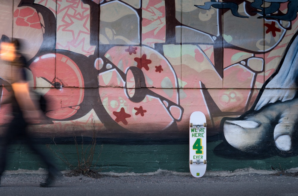 person walking near murial and white skateboard