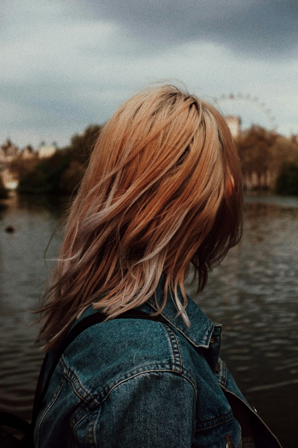 woman in blue denim jacket in front of body of water